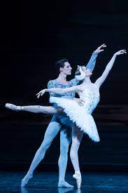 two ballet dancers, a male and a female at a recital,in blue leotards.